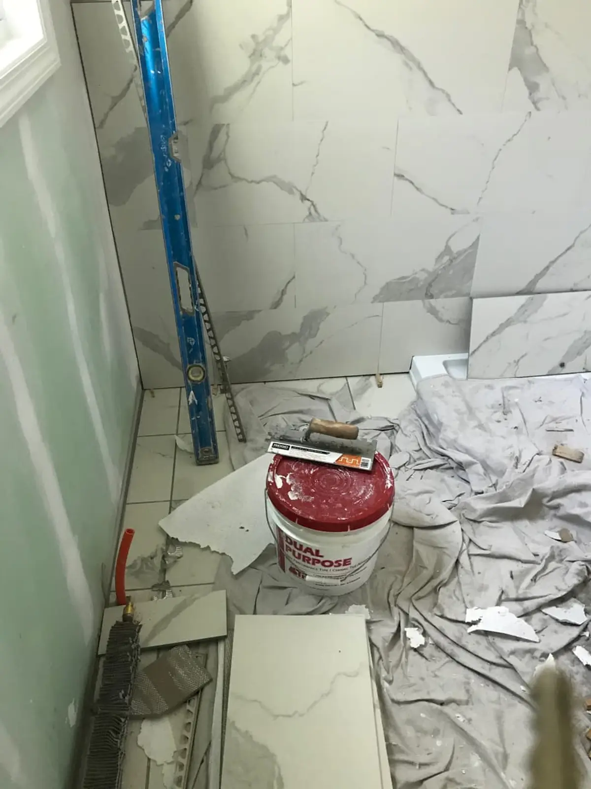 Selling a fire-damaged house in Islip: bathroom mid-renovation with new marble-look tile going in