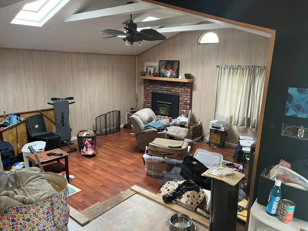 Selling a house with tenants in it in Islip: cluttered living room with a brick fireplace and skylights