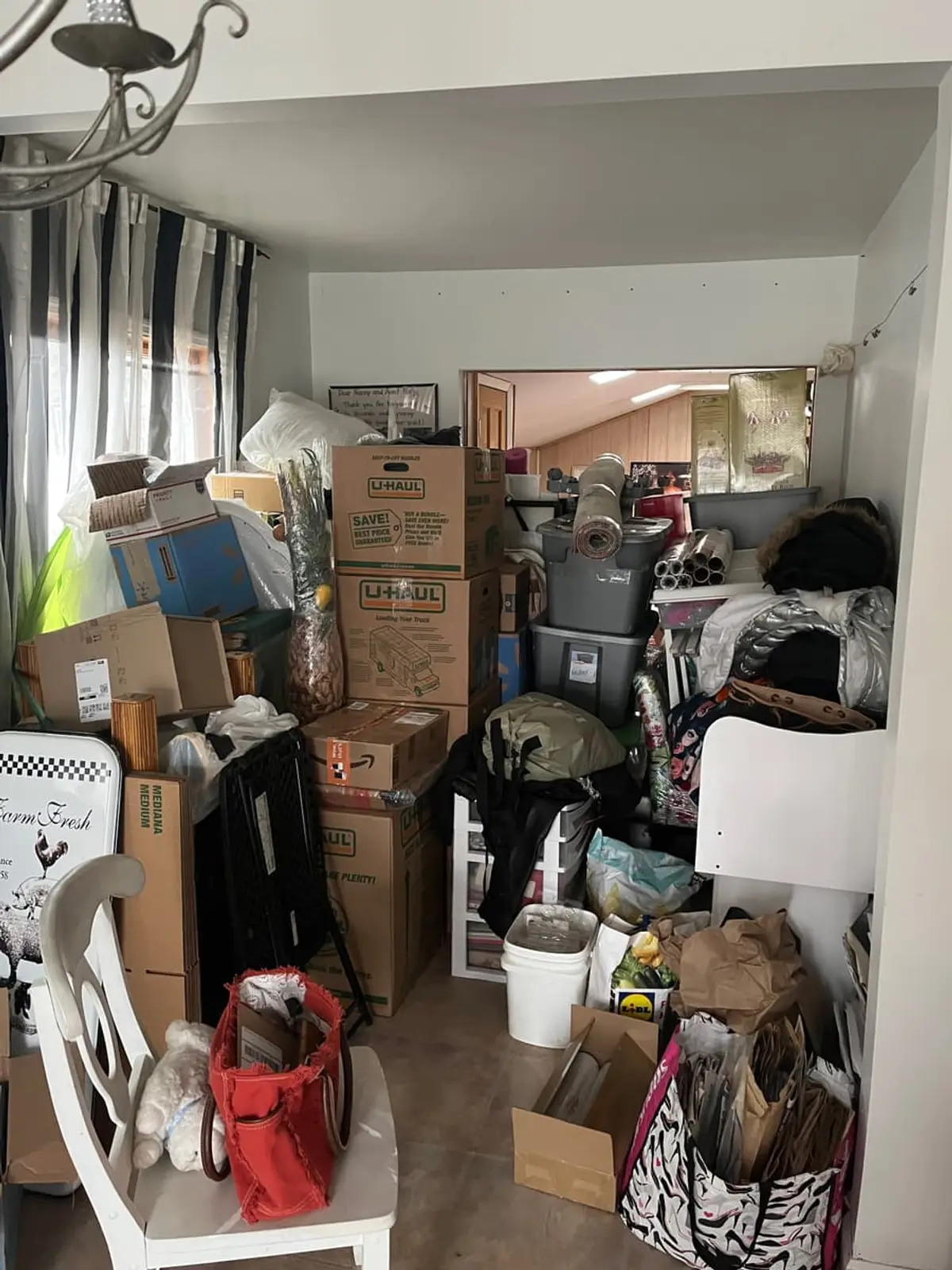 Selling a hoarder house in Islip: front room stacked with boxes, bins and bags