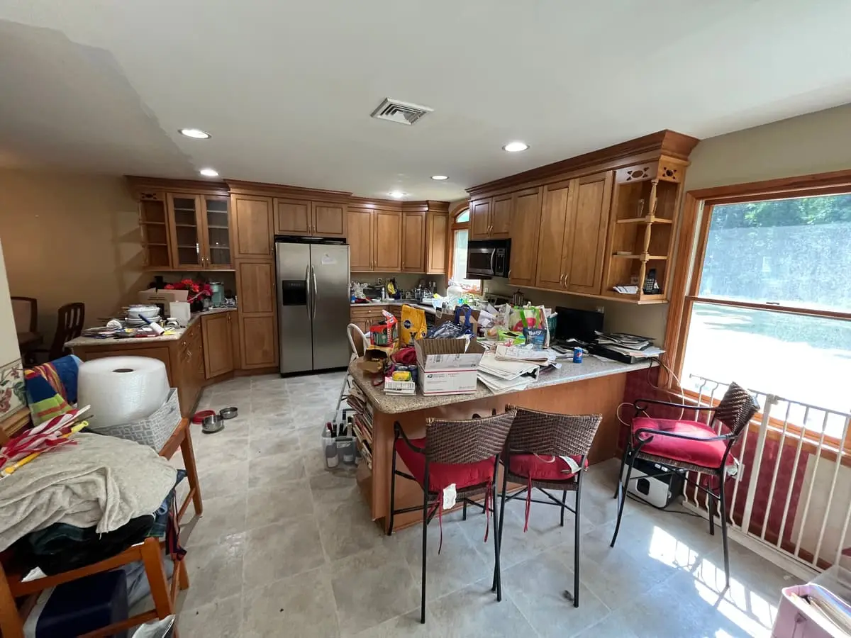 Selling with a non-paying tenant in Islip: occupied kitchen with wood cabinets and counters buried in belongings