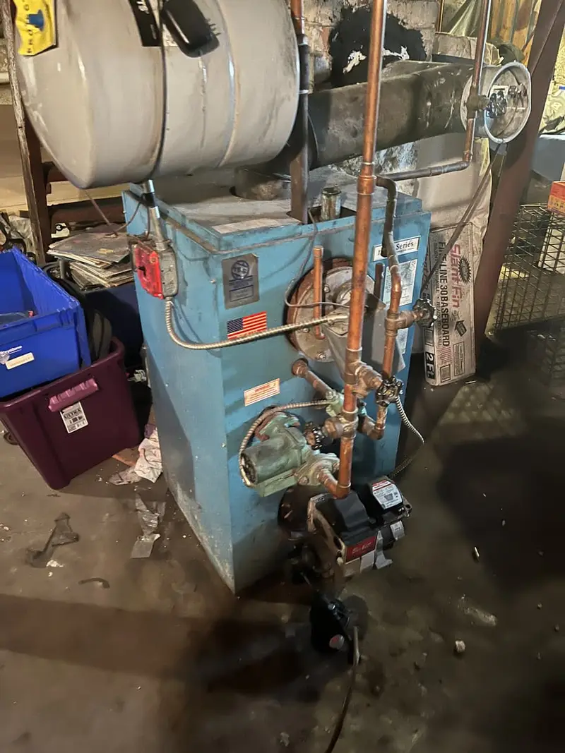Old oil boiler and pipes in an unfinished basement, Islip, NY