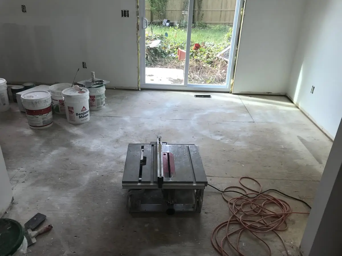 Selling a house with unpermitted work in Islip: room stripped to the subfloor with a tile saw and buckets