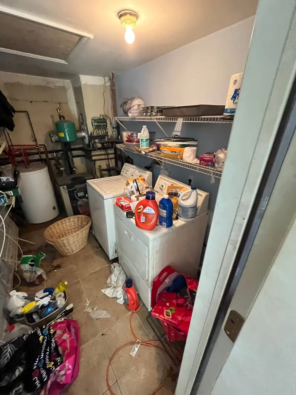 Selling a house with a reverse mortgage in Islip: utility room with an old boiler, washer and piled laundry