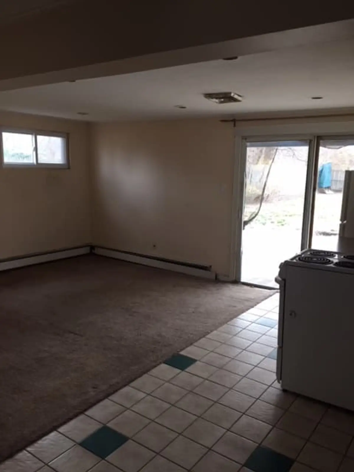 Downsizing or retiring in Islip: vacant dated kitchenette with checkered tile and worn carpet